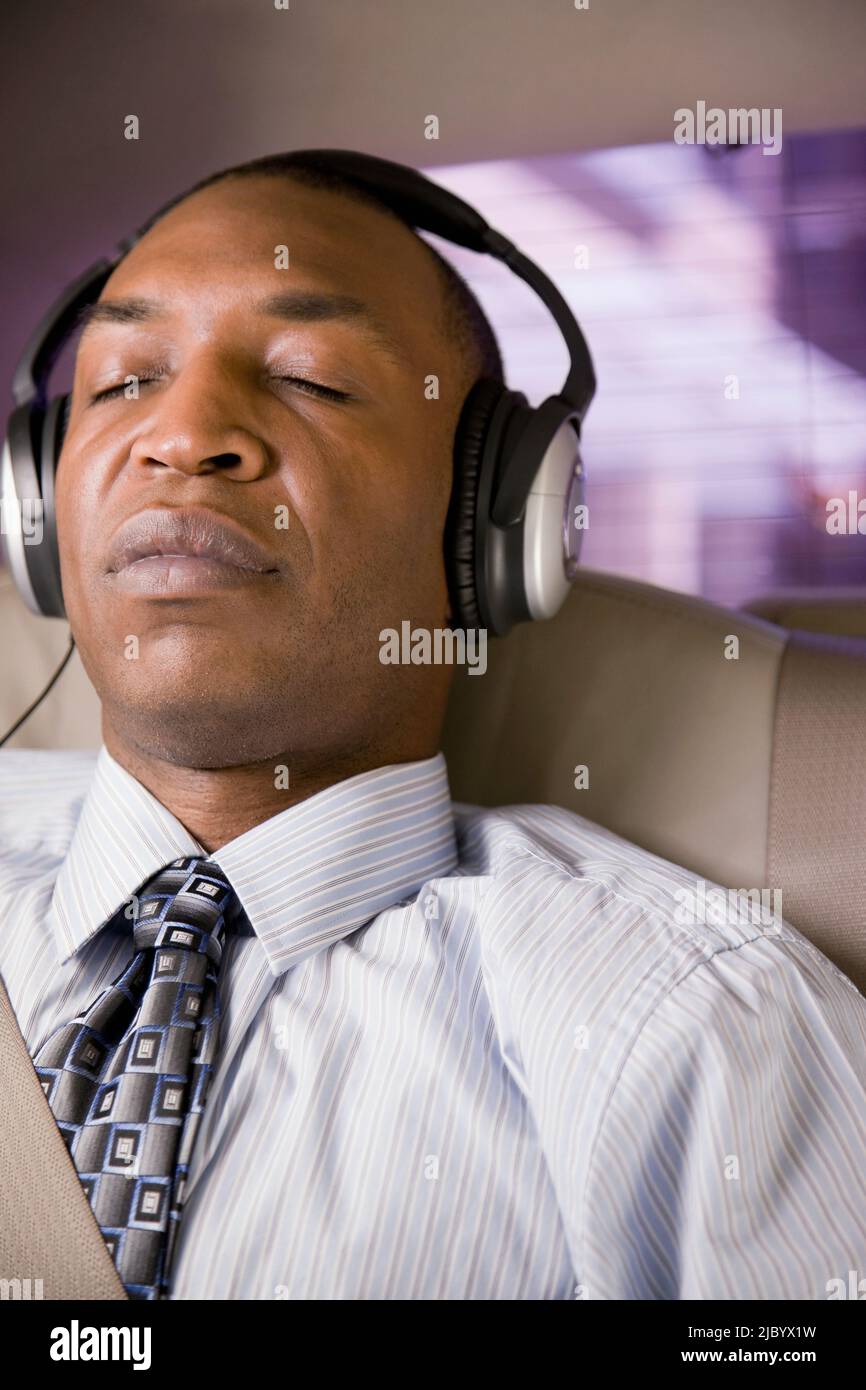 African businessman listening to headphones in back seat of car Stock Photo Alamy