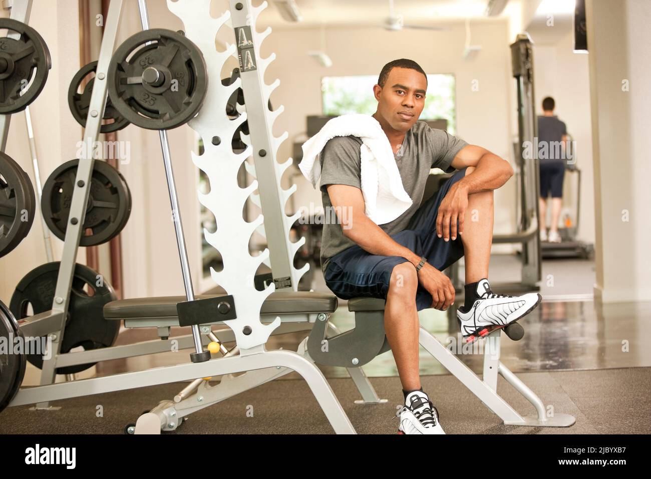 African American man resting in health club on weight-lifting bench Stock Photo