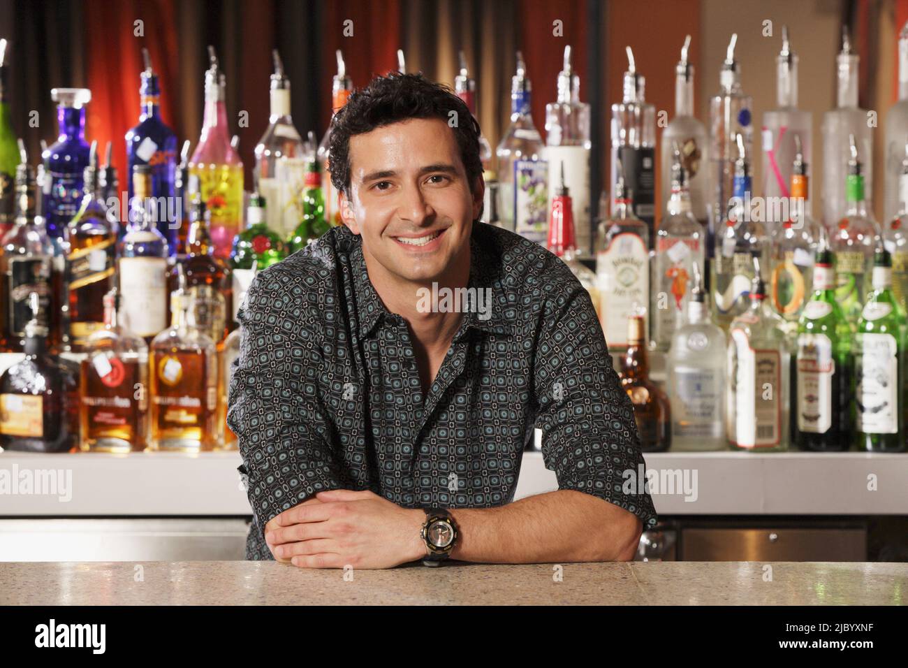 Hispanic male bartender leaning on bar Stock Photo