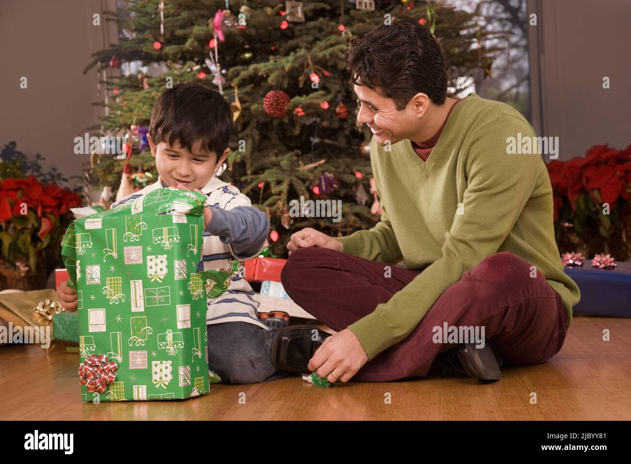 Hispanic father watching son open Christmas gift Stock Photo Alamy