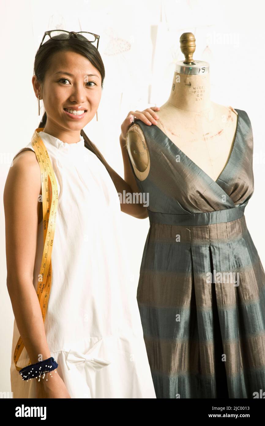 Asian female fashion designer next to dress dummy Stock Photo - Alamy