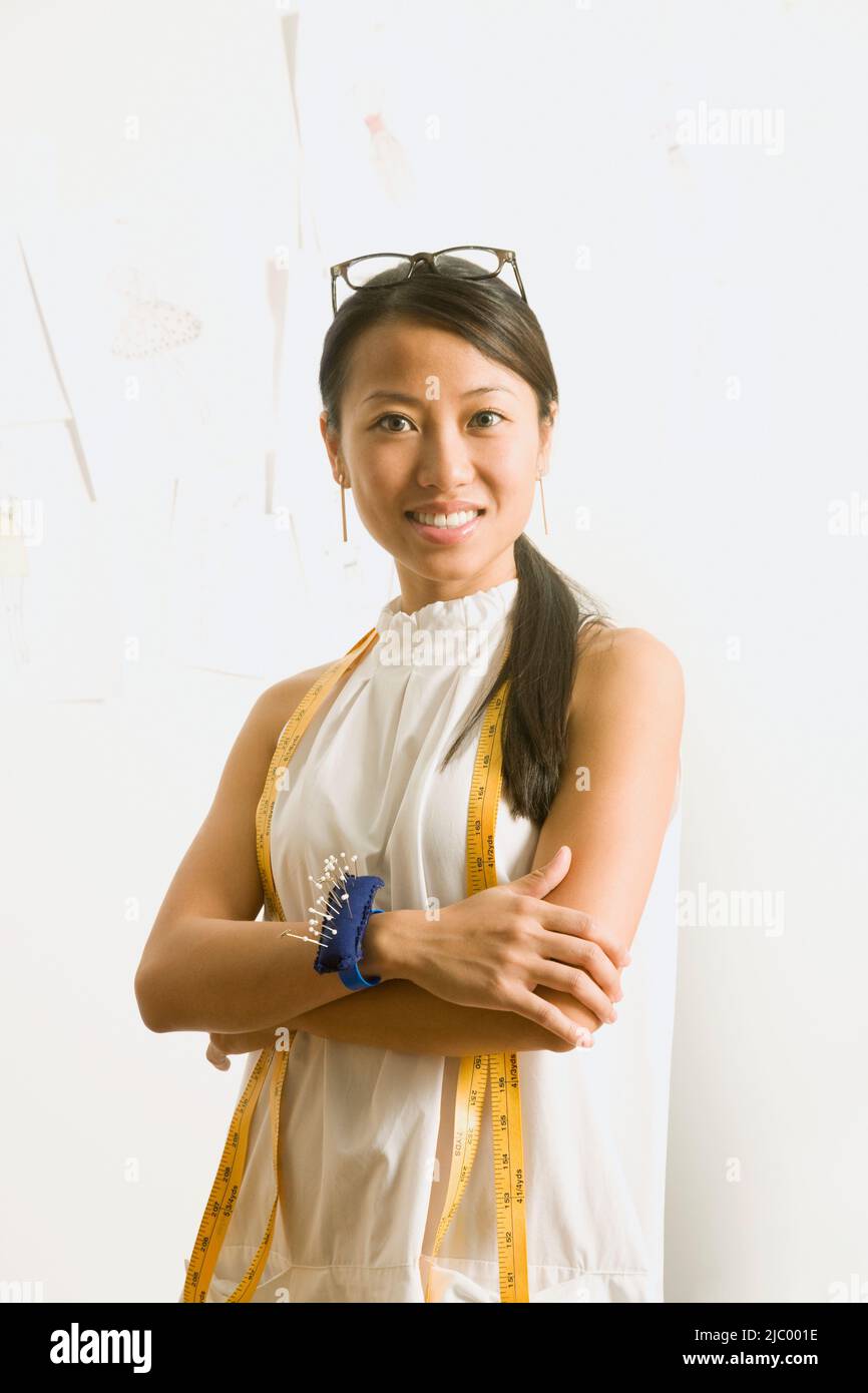 Asian female fashion designer with tape measure around neck Stock Photo