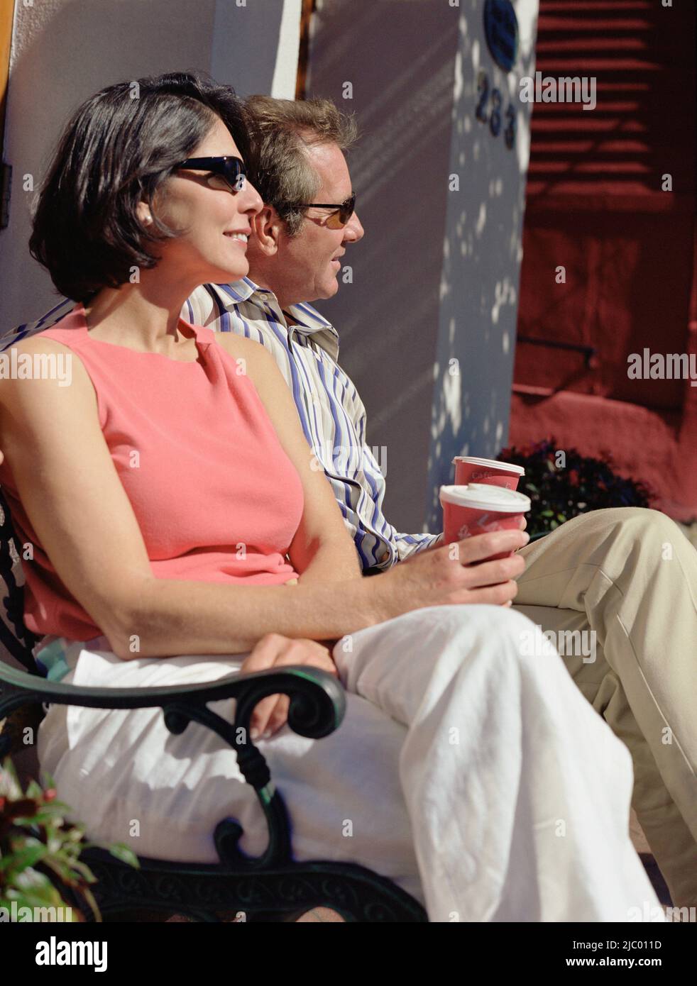 Middle-aged couple sitting on bench drinking coffee Stock Photo