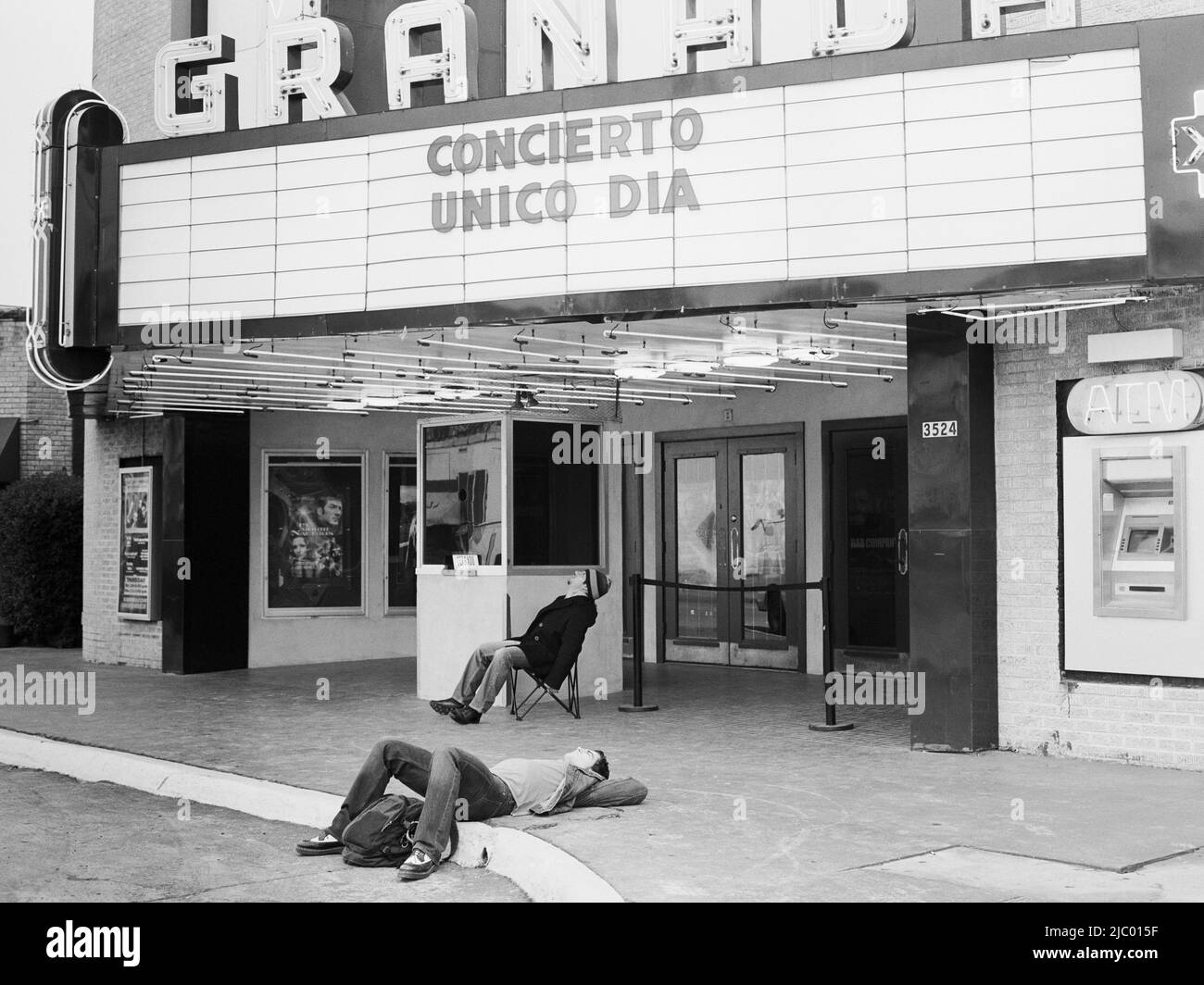 Man laying on ground in front of movie theater Stock Photo