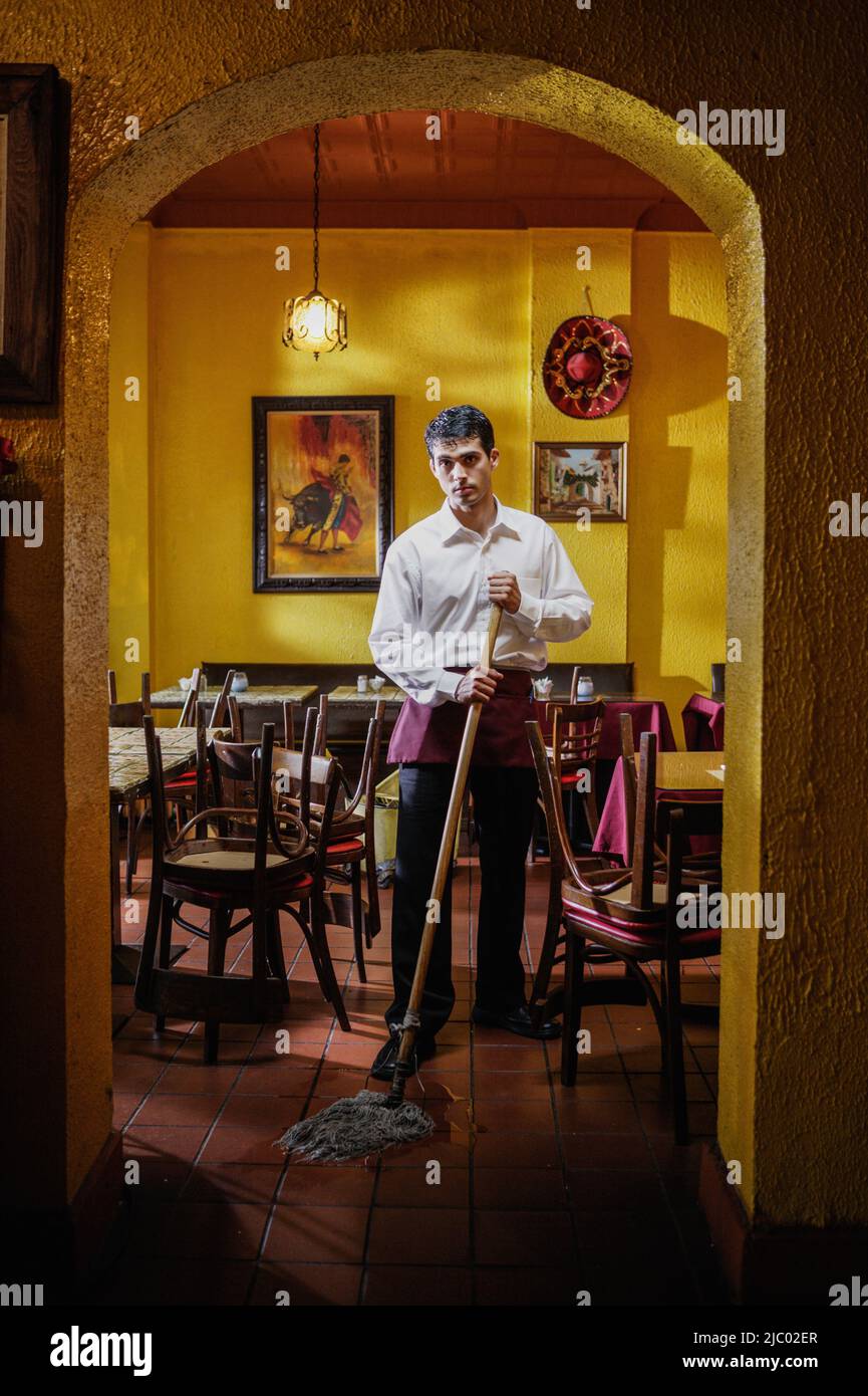 Portrait of man mopping restaurant floor Stock Photo