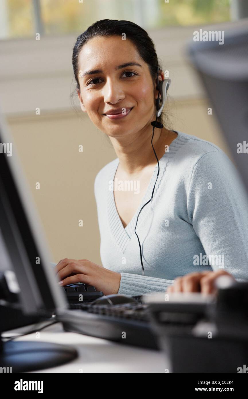 Businesswoman using a computer and talking on a headset Stock Photo