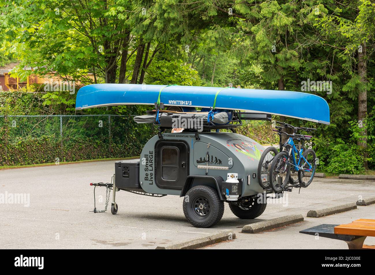 A teardrop camping trailer loaded with bikes, camping gear and a canoe parked at Porteau provincial campground near Squamish BC, Canada. Stock Photo