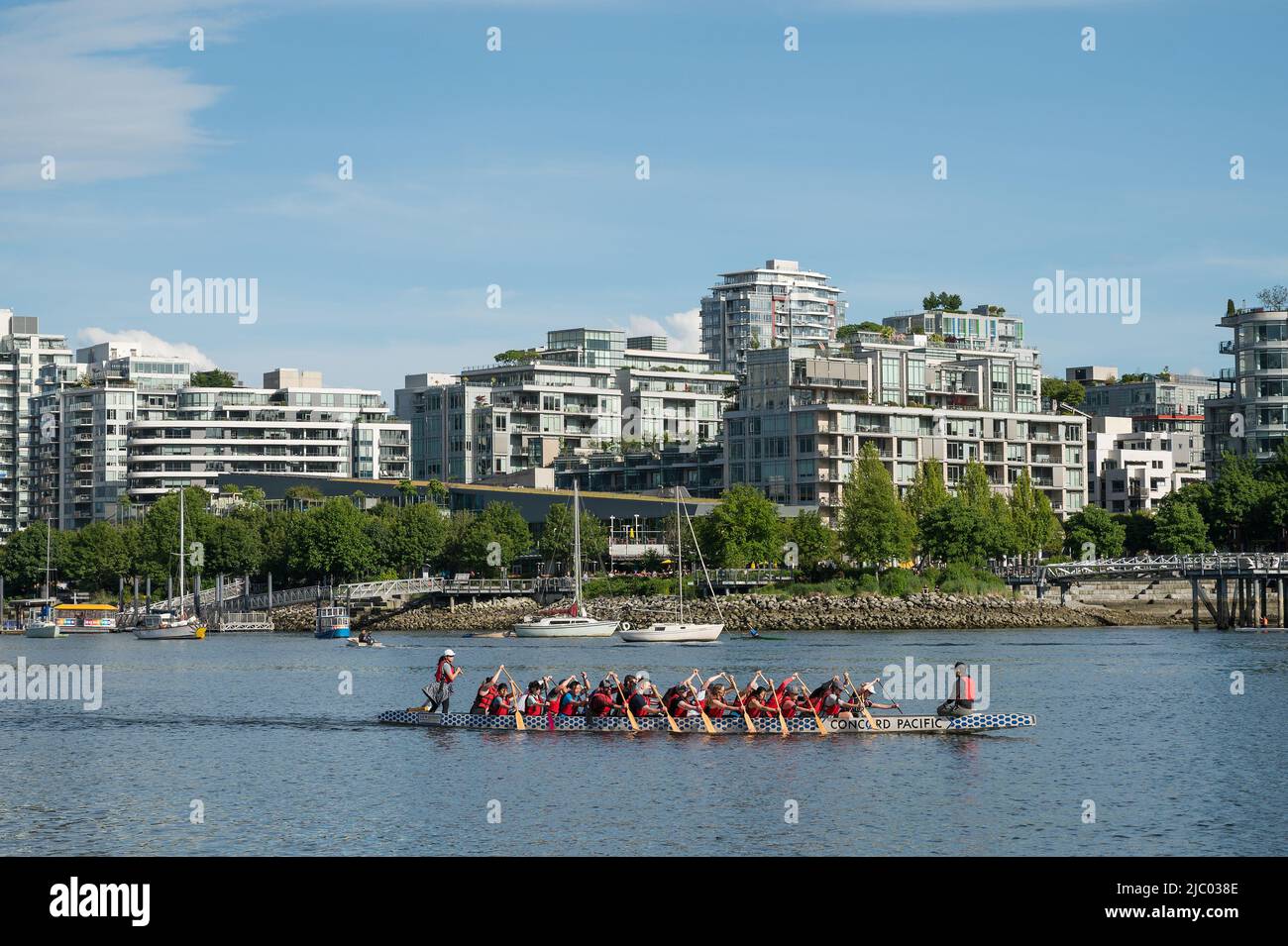 A dragon boat war canoe paddles through VancouverÕs False Creek in the Yaletown neighbourhood.  Vancouver BC, Canada. Stock Photo