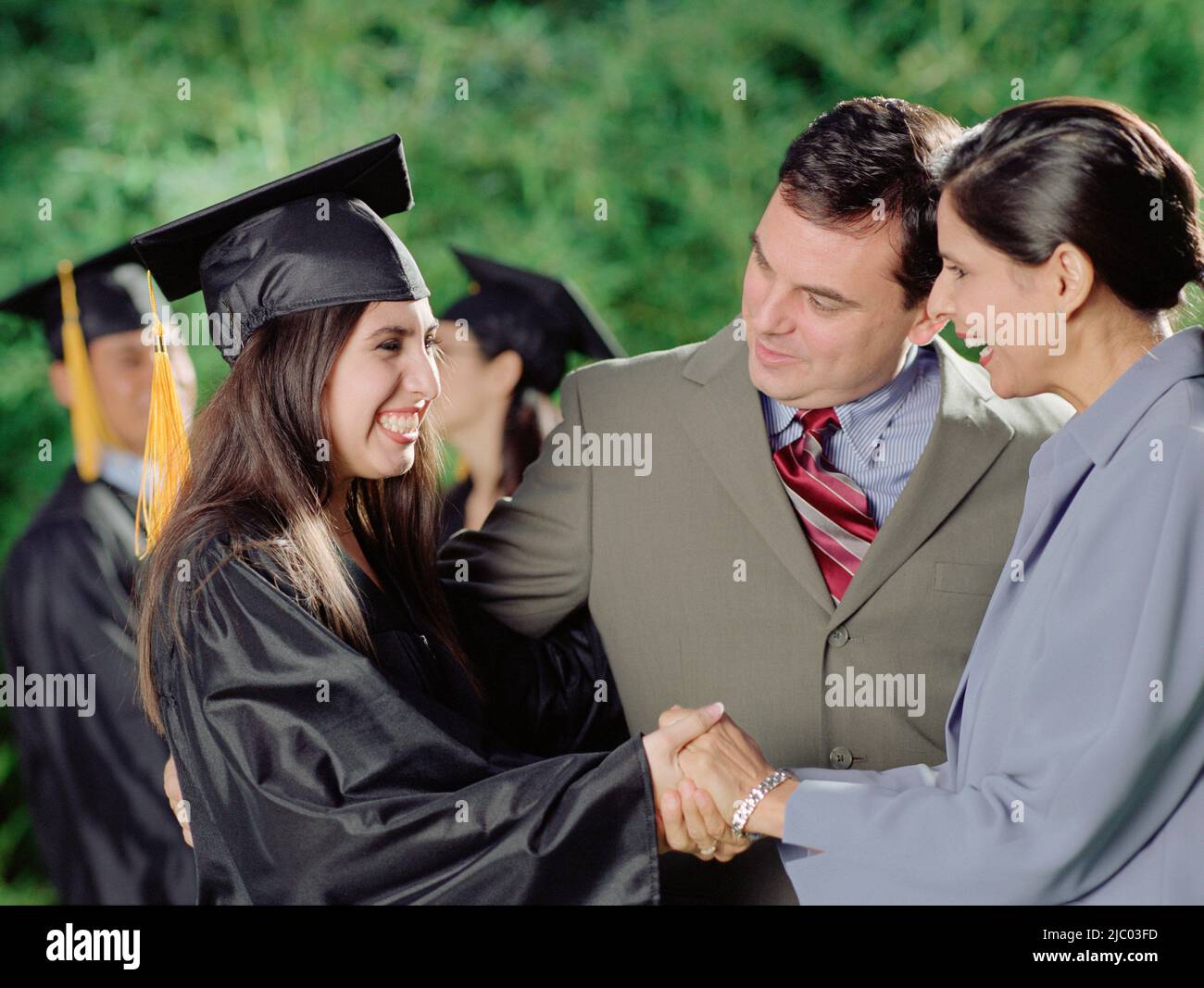 Mother and father hugging their graduate daughter Stock Photo