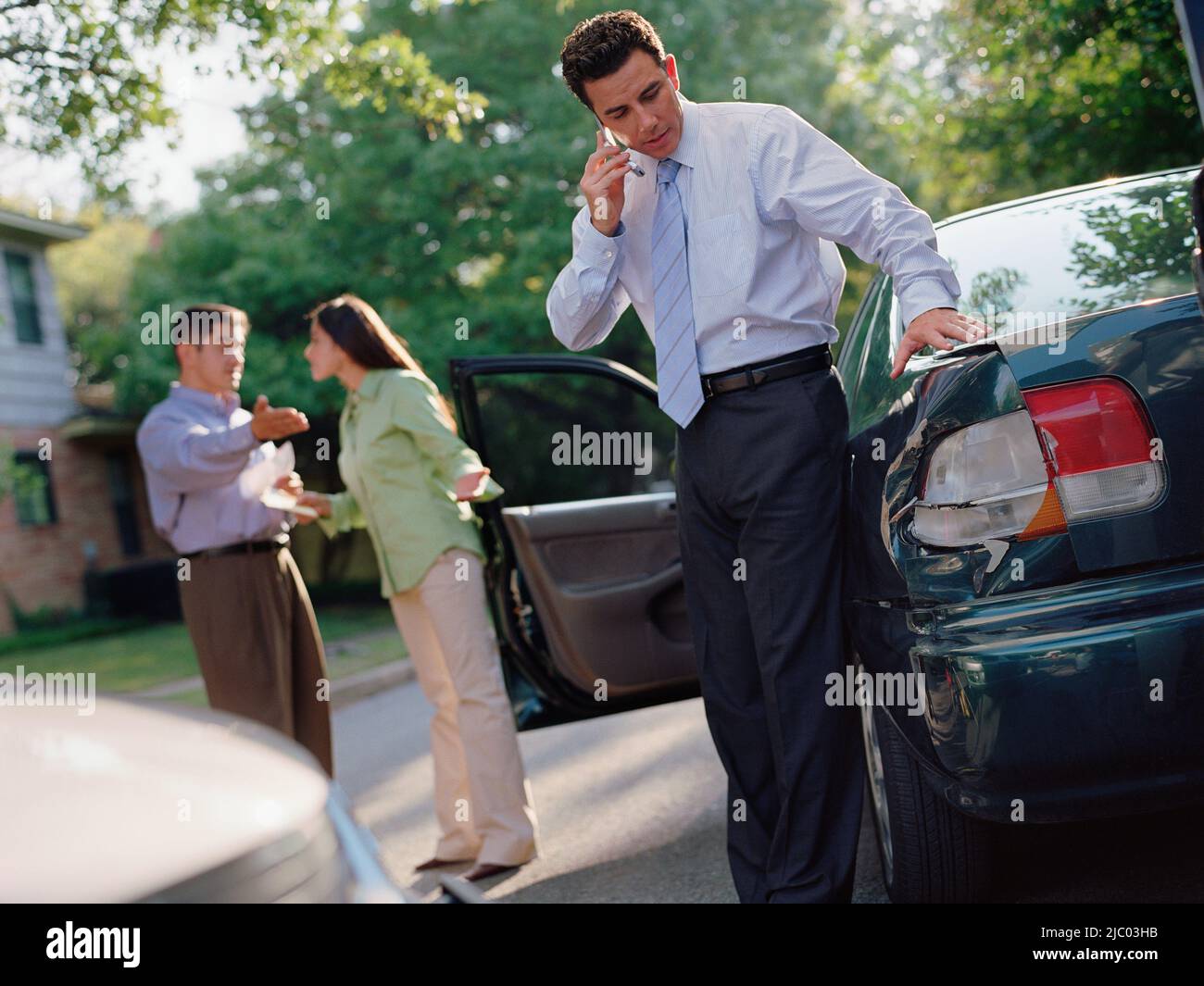 Businessman talking on his cell phone by a car accident Stock Photo