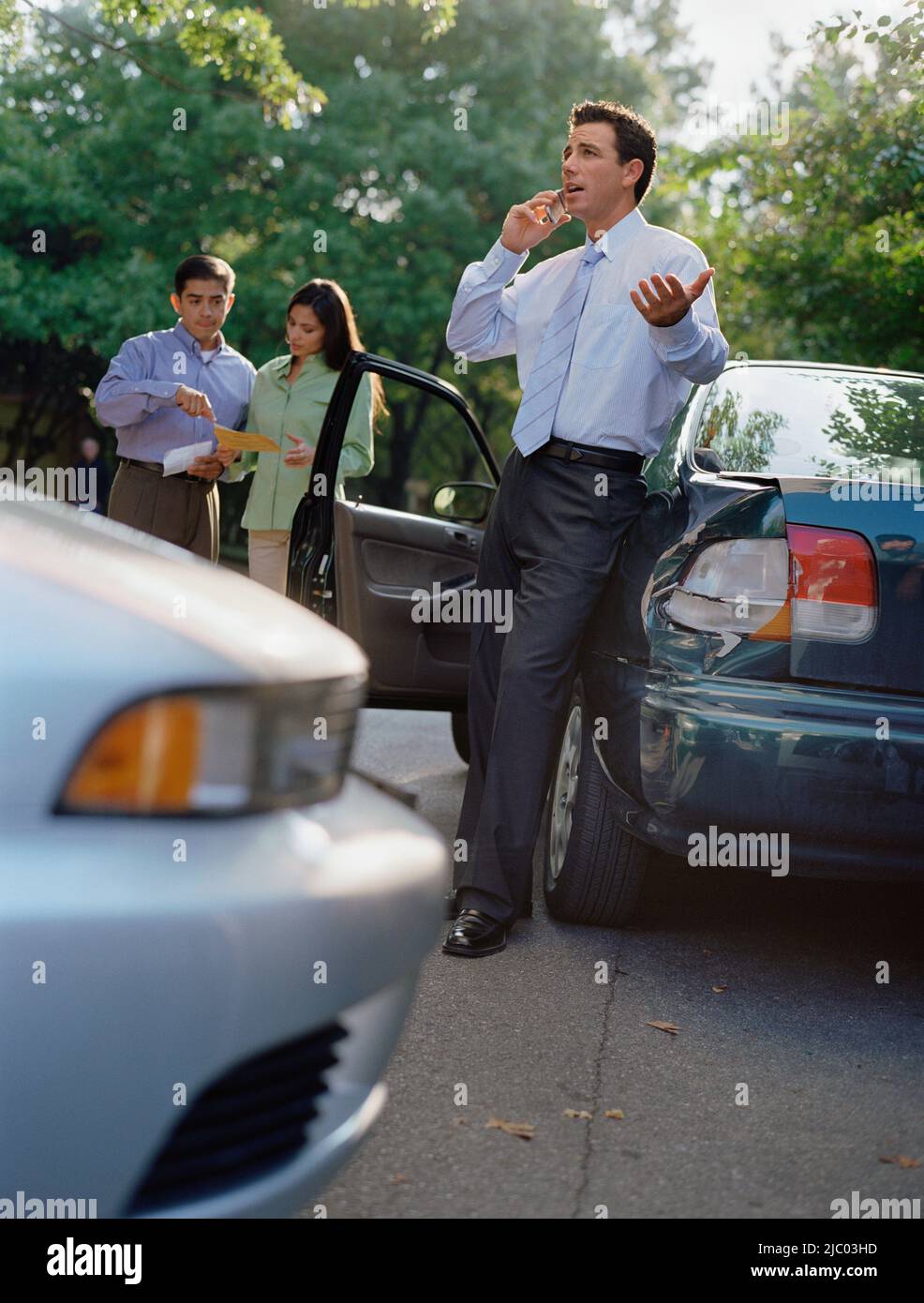 Businessman talking on his cell phone by a car accident Stock Photo