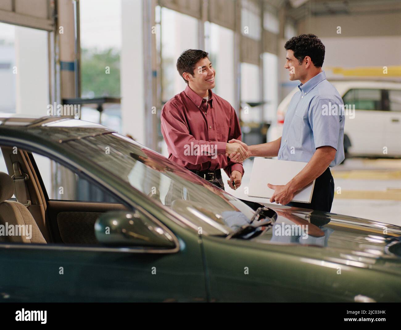 Car salesman and customer shaking hands Stock Photo