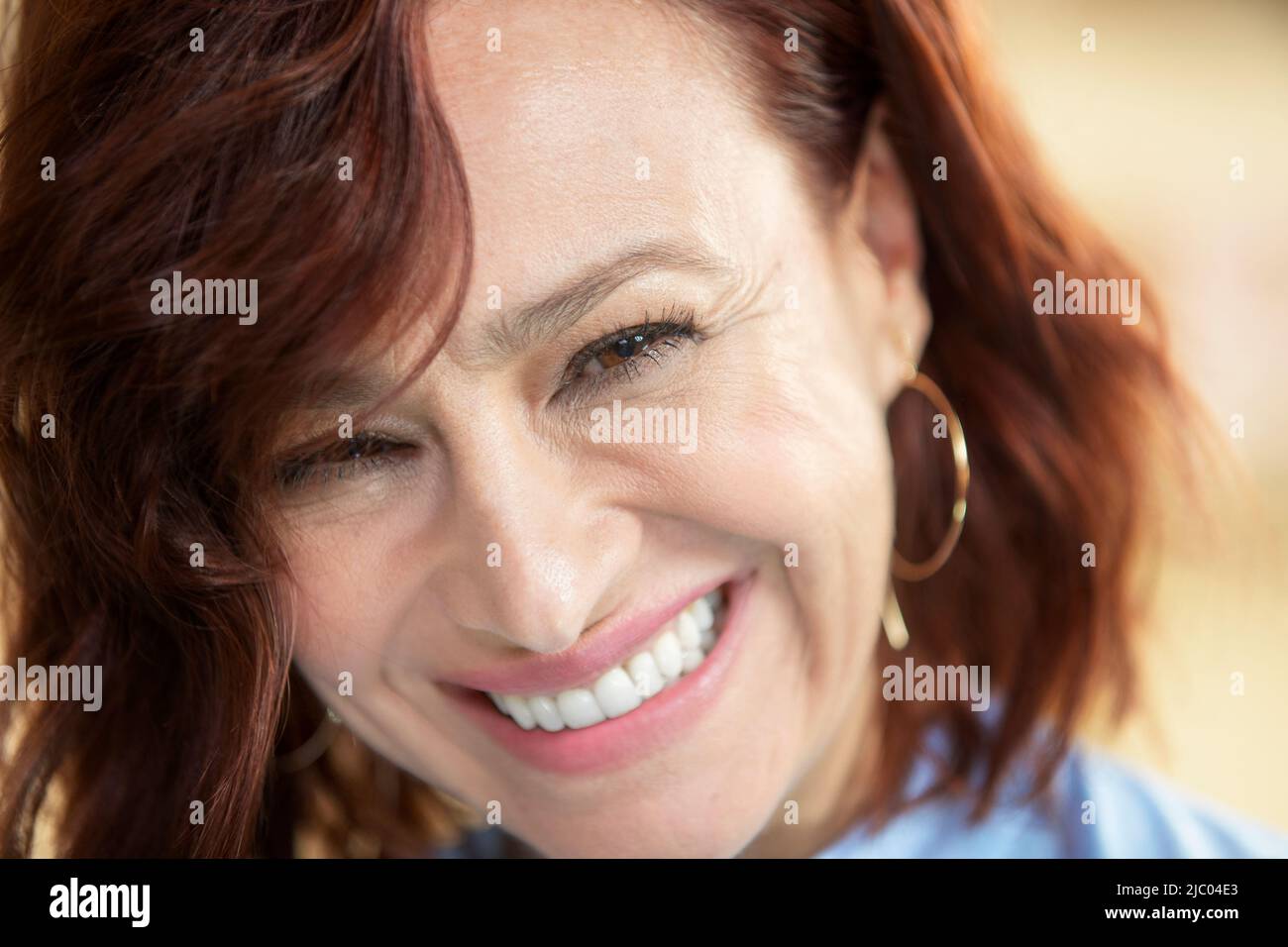 Closeup portrait of a middle-aged woman with redhead looking into camera with her chin down. Stock Photo
