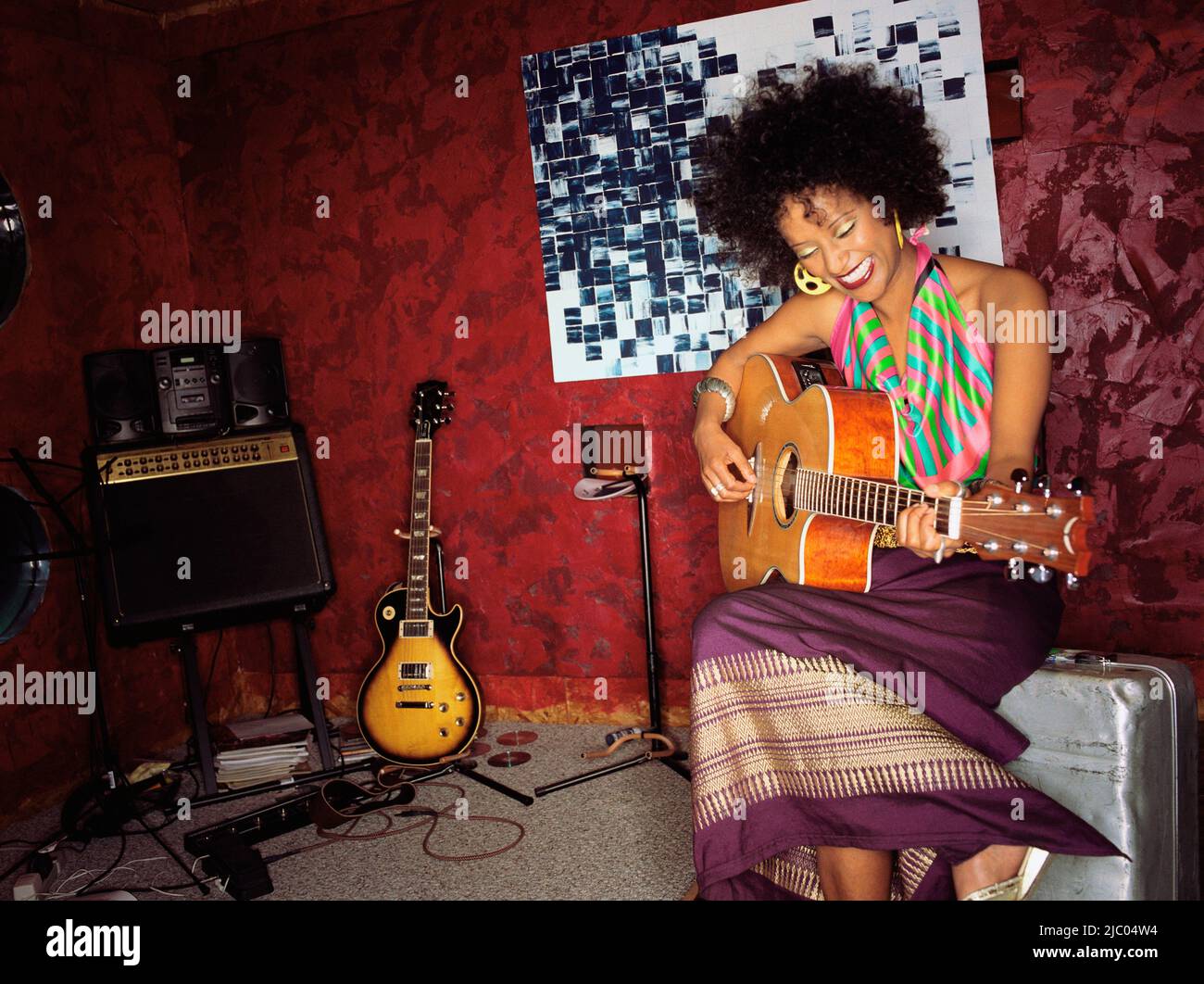 Young woman playing guitar in studio Stock Photo