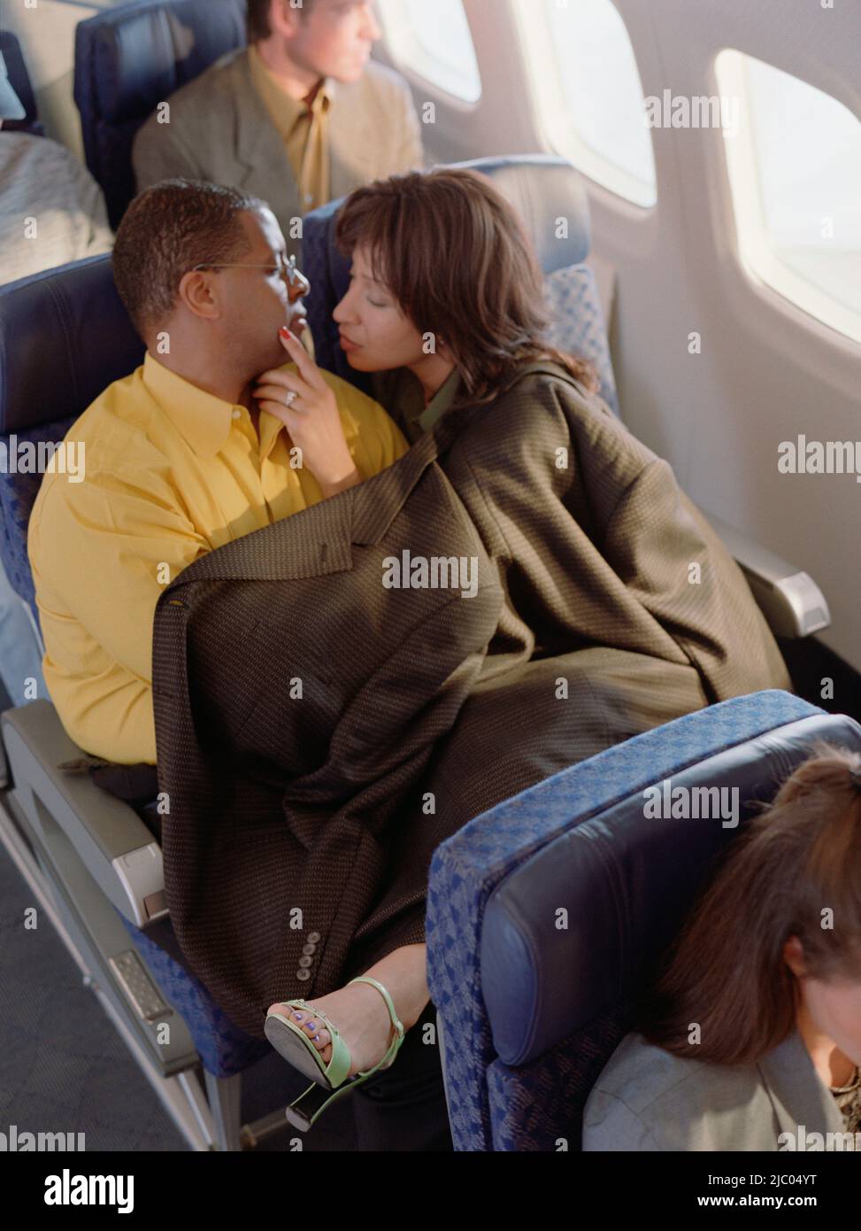 Mature couple cuddling on airplane Stock Photo