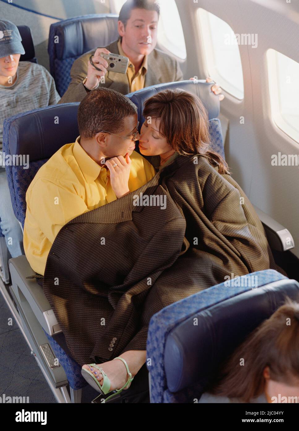 Mature couple cuddling on airplane Stock Photo