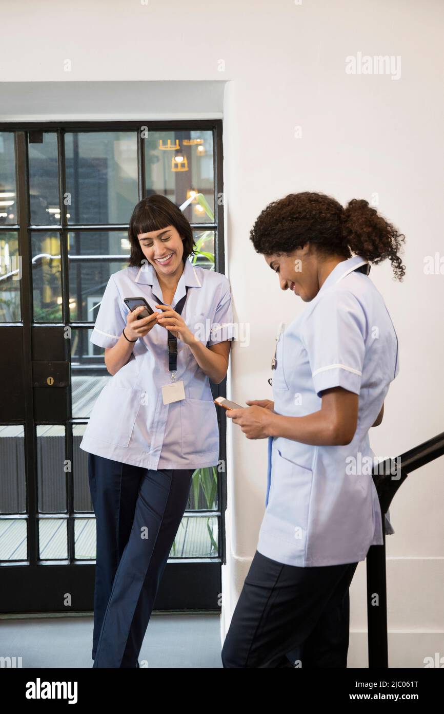 Women in healthcare industry using cell phones in hallway Stock Photo