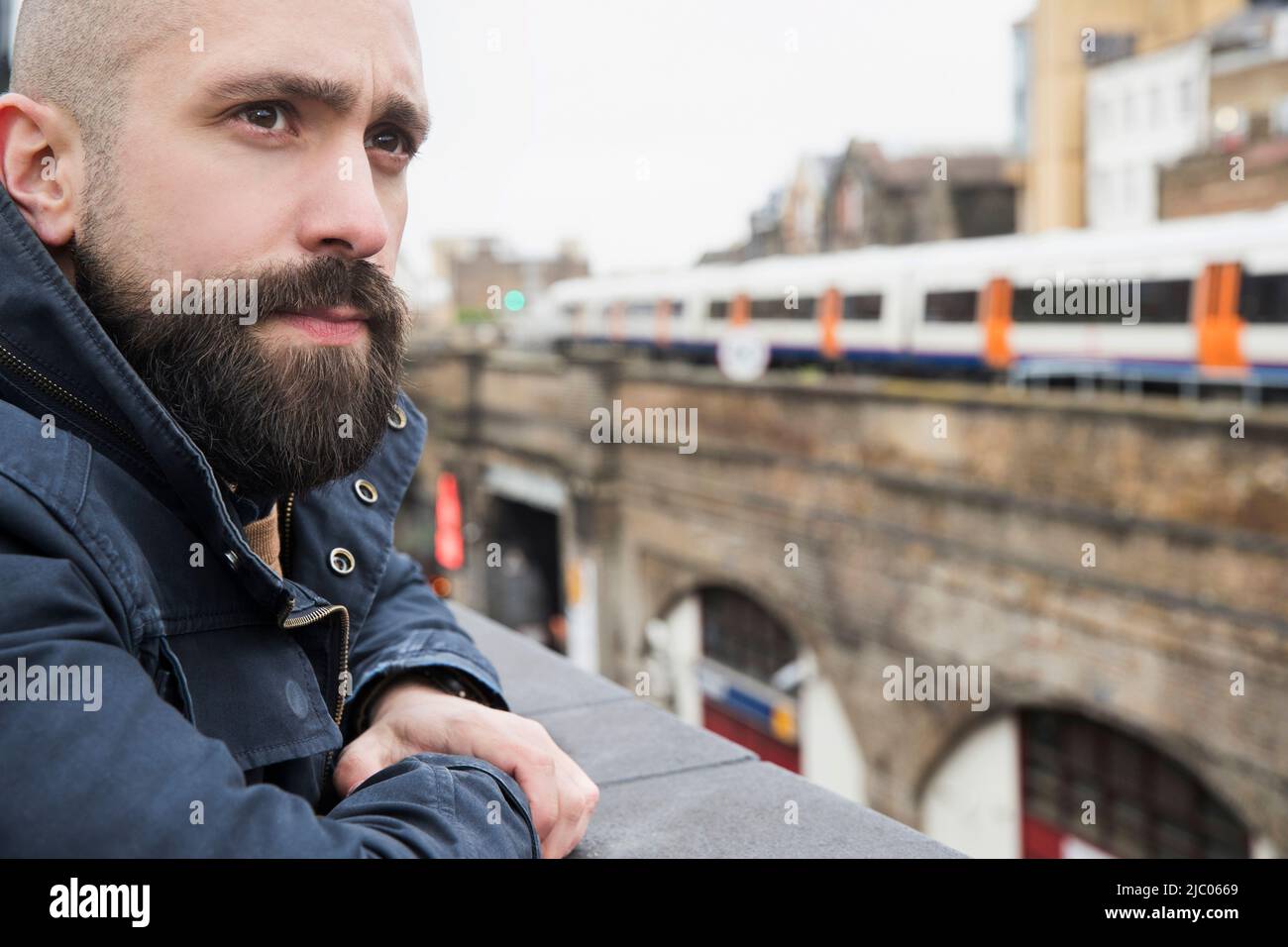 Man looking over ledge of building from rooftop patio Stock Photo