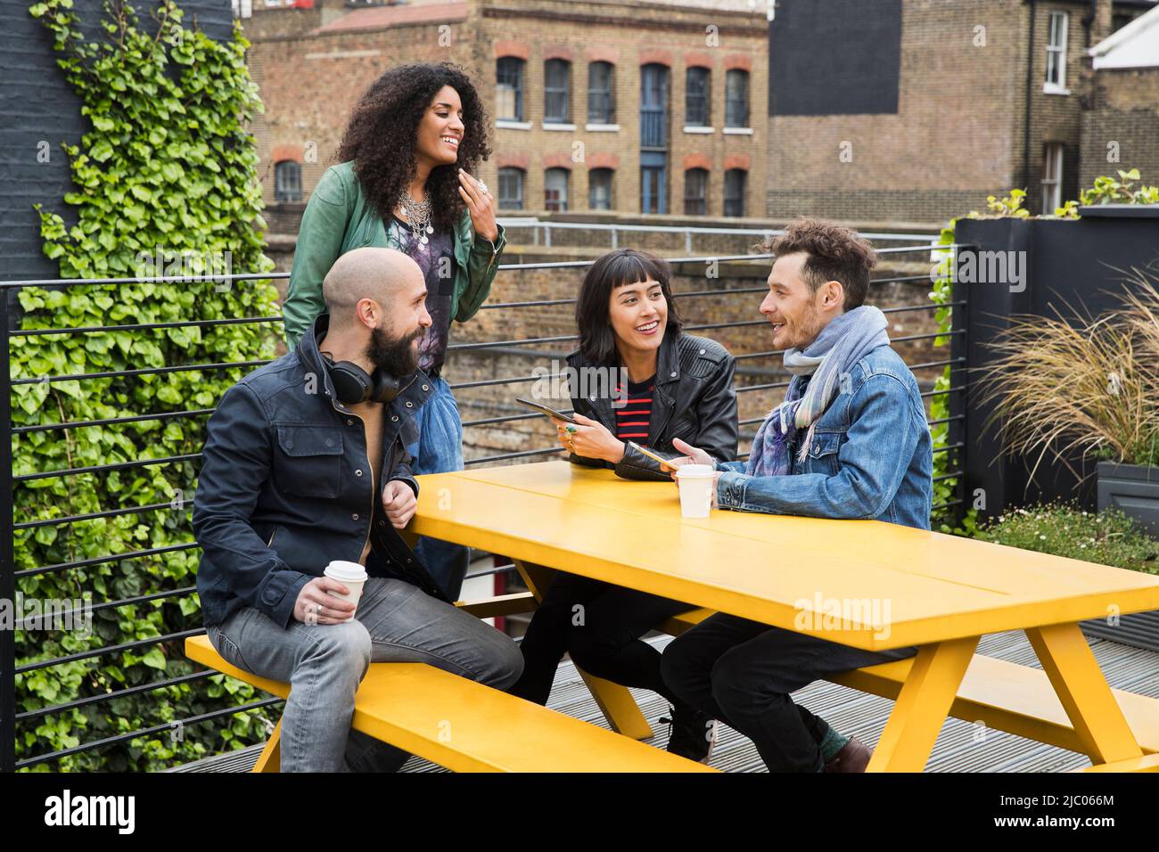 Group of friends working on tablets at outdoor patio table in co-working space Stock Photo