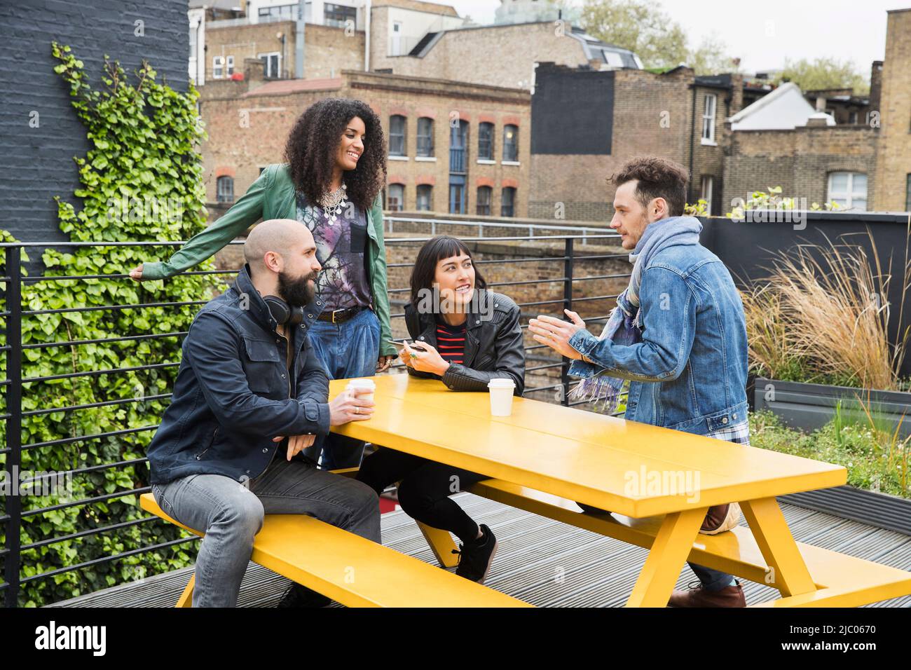 Group of friends working on tablets at outdoor patio table in co-working space Stock Photo