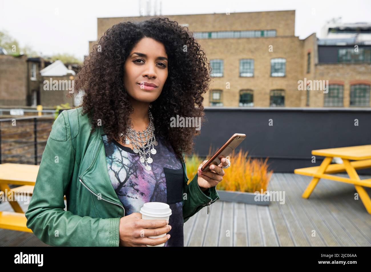 Portrait of Woman on rooftop patio with cell phone Stock Photo