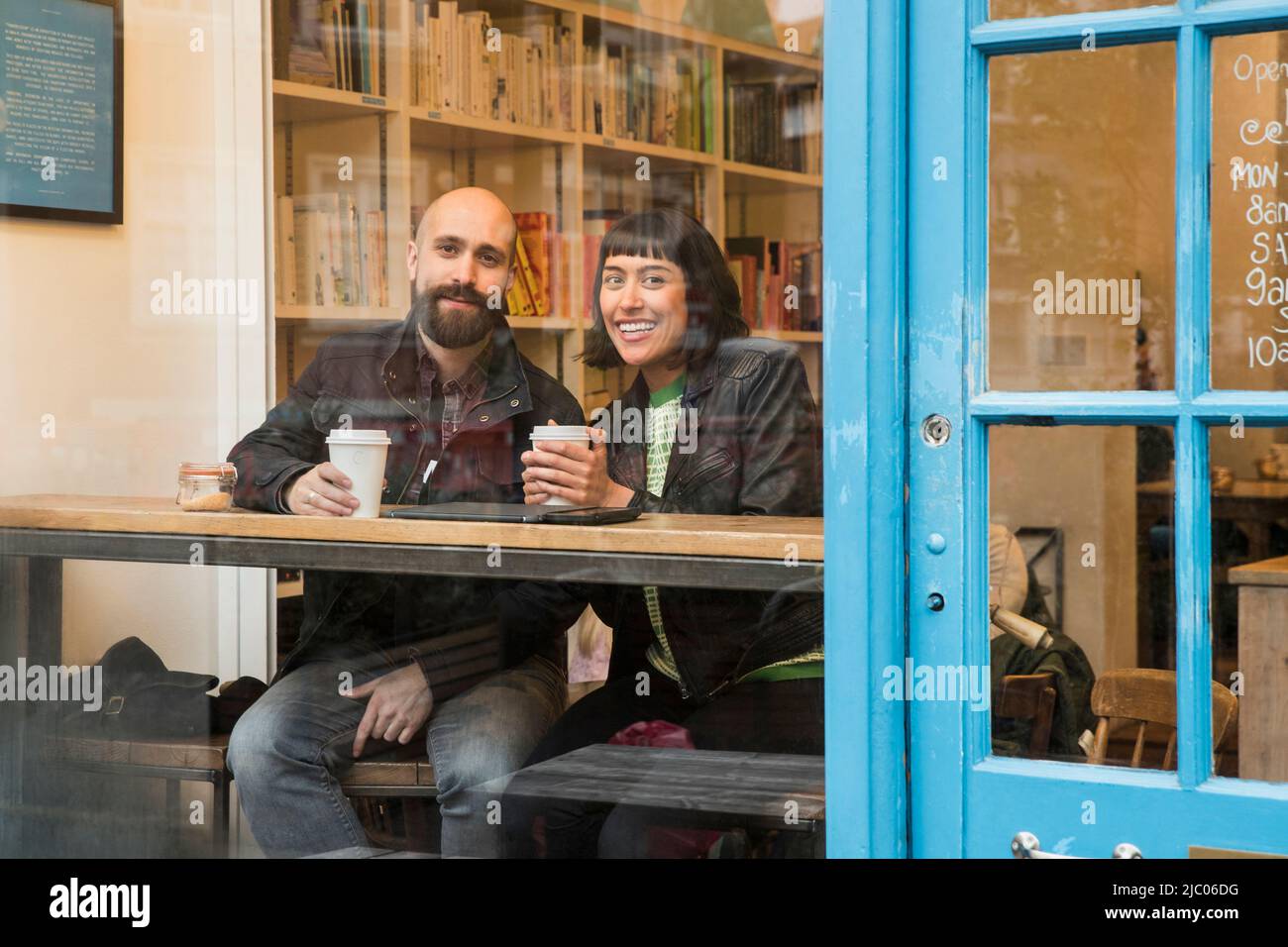 Friends sitting in window of cafe with tablet Stock Photo