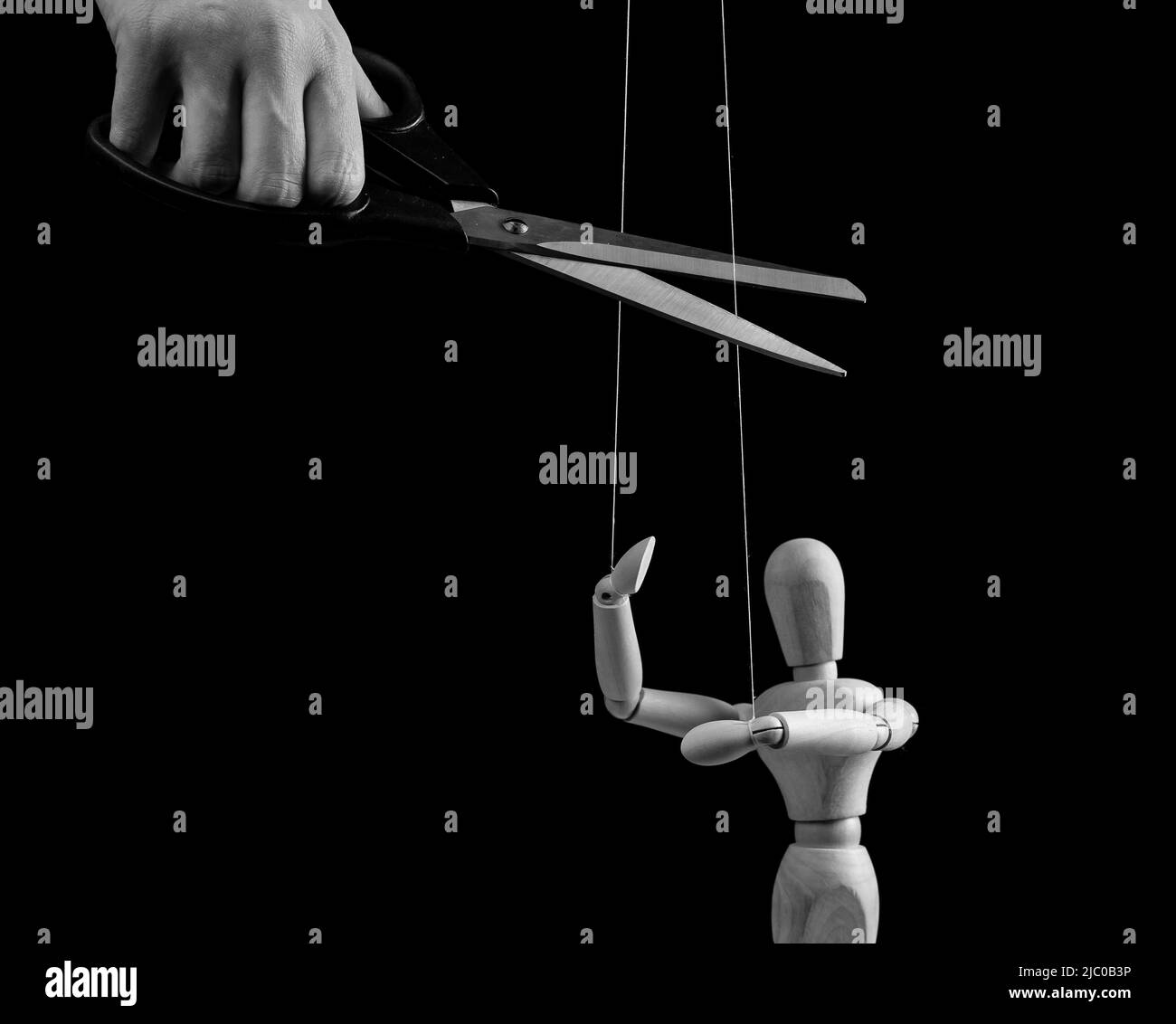 Hand cutting strings over puppet with scissors. Manipulation, negative influence, control stop concept. Overcoming addiction. Black and white. High quality photo Stock Photo