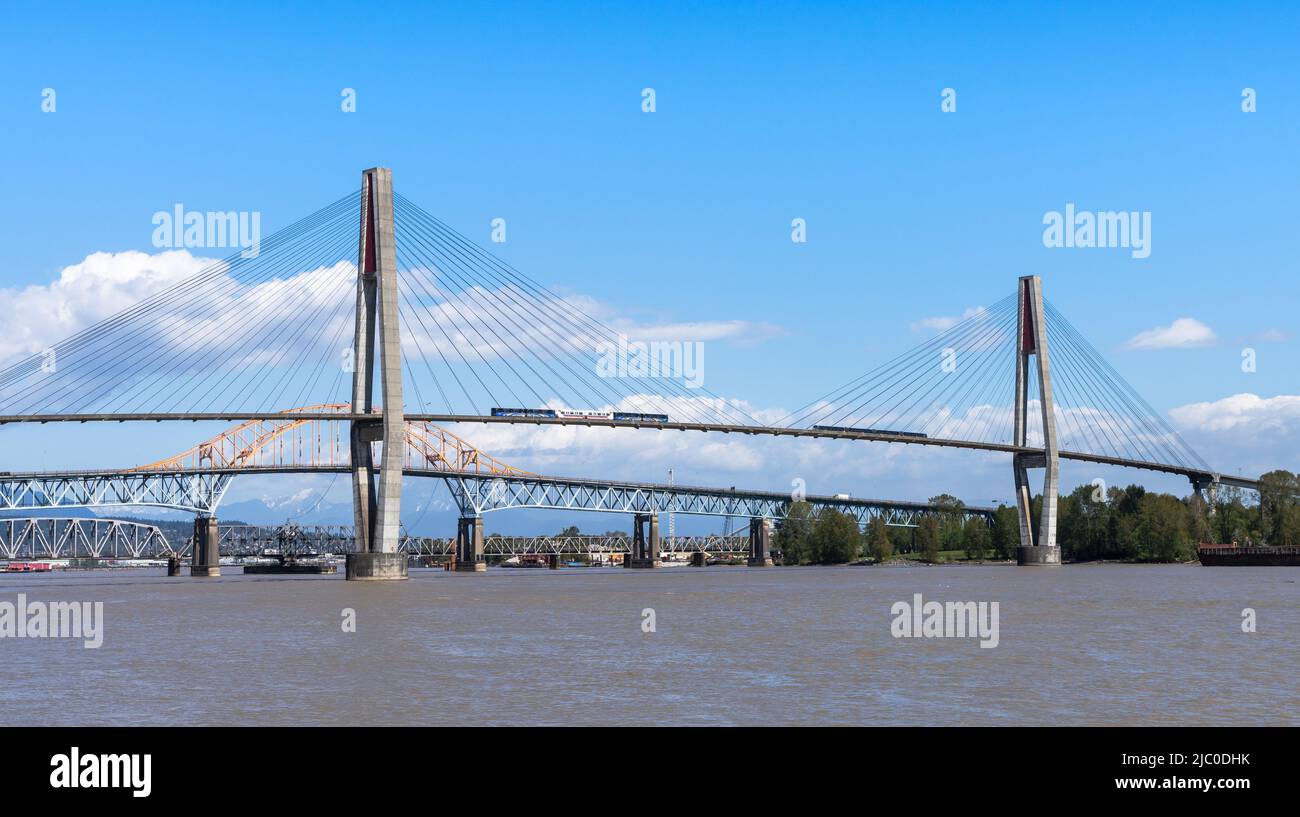 New Westminster, BC, Canada - April 22 2021 : SkyTrain passing the SkyBridge. A cable-stayed bridge in Metro Vancouver. Stock Photo