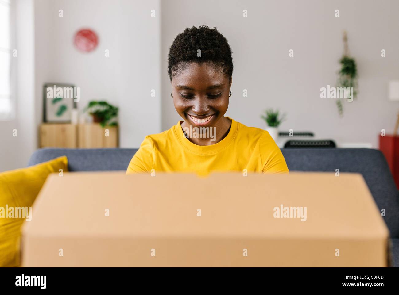 Happy african american woman unpacking package after online shopping Stock Photo