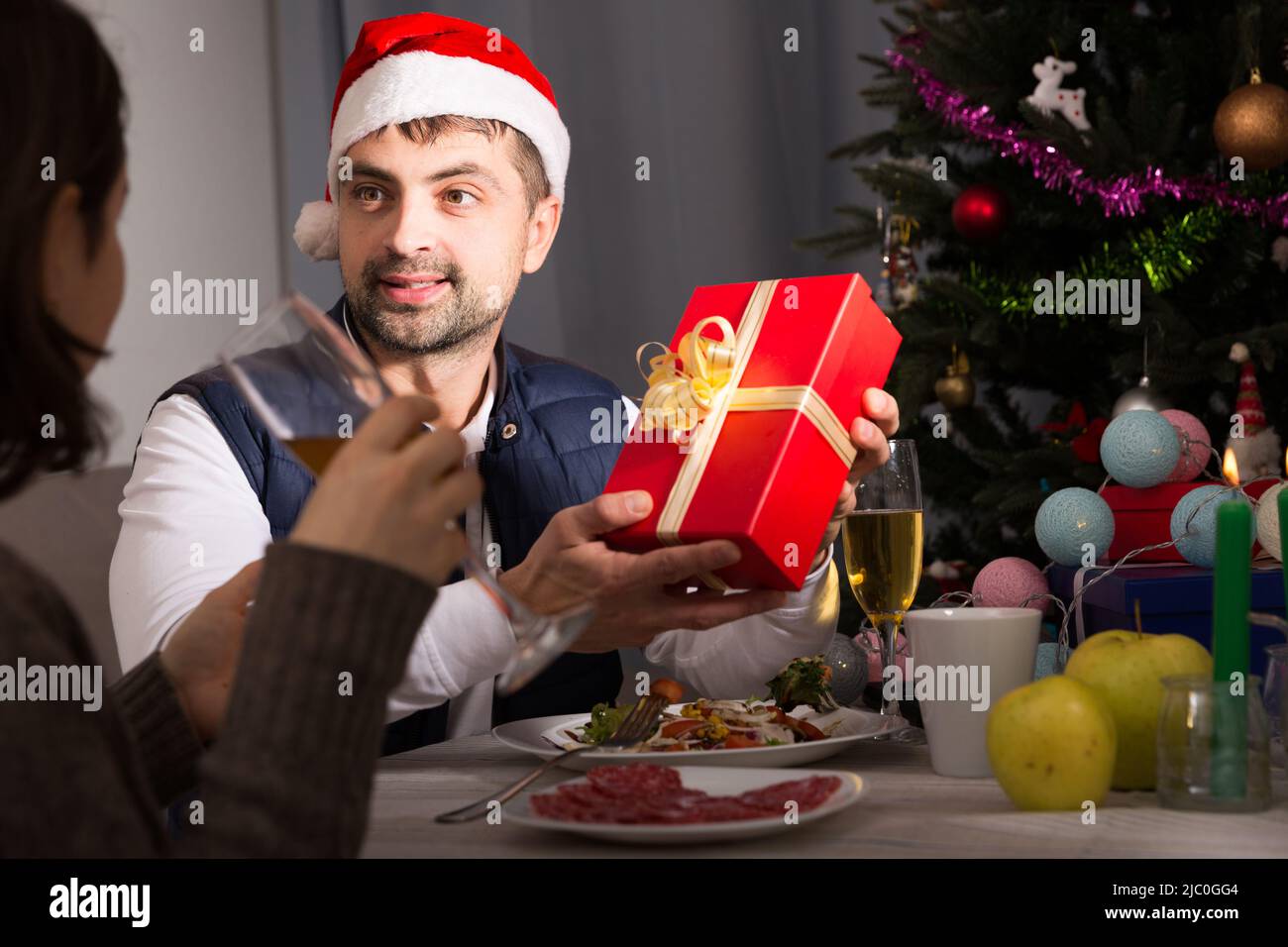 Male in hat giving present to woman during dinner Stock Photo