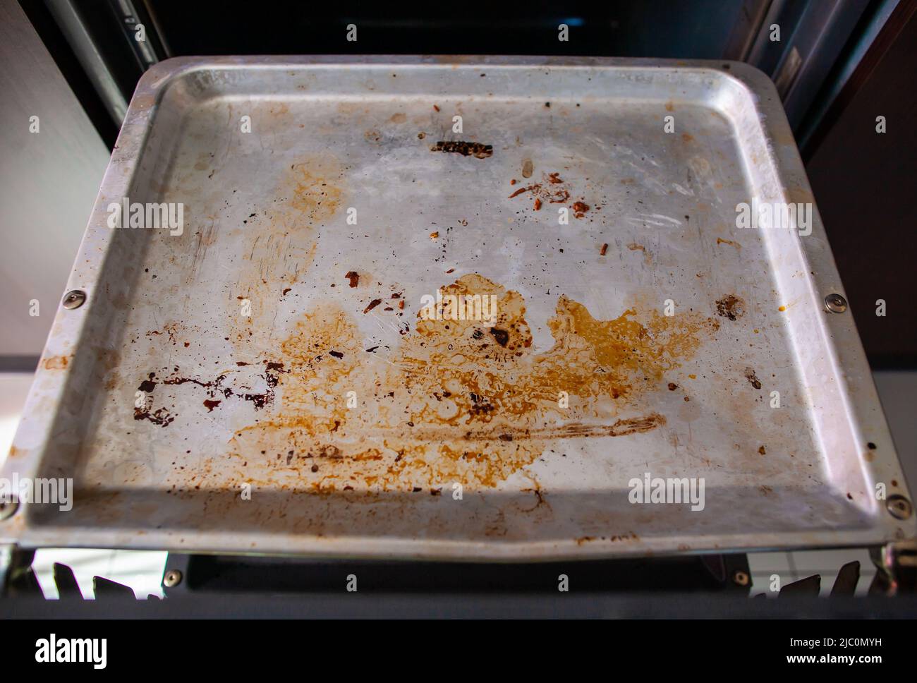 Dirty baking tray in opened oven top down view Closeup of metal oven