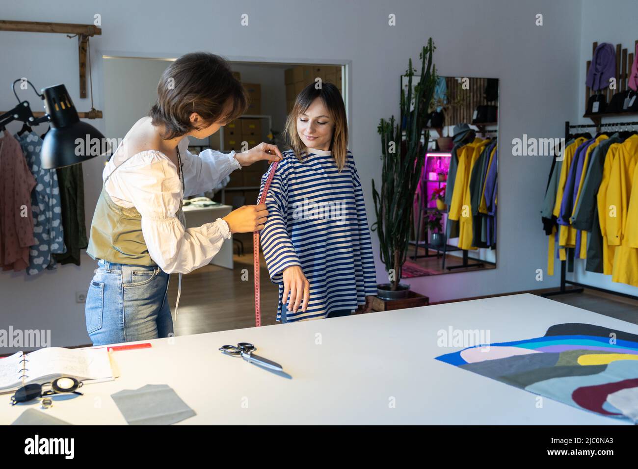 Fashion designer woman takes measurements with measuring tape of client ...
