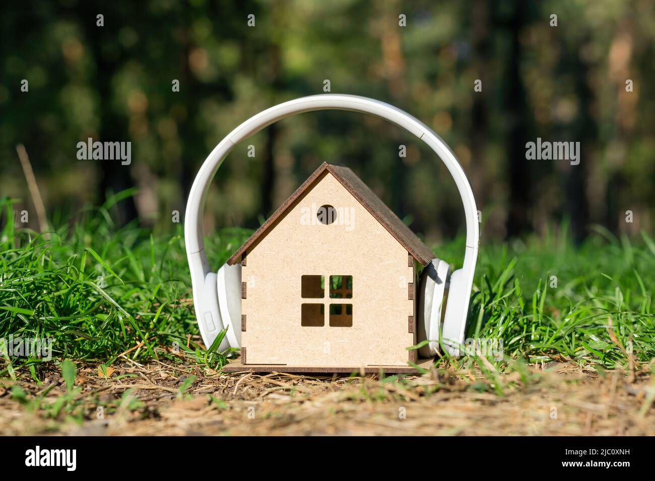 White wireless headphones on a miniature wooden house model in the