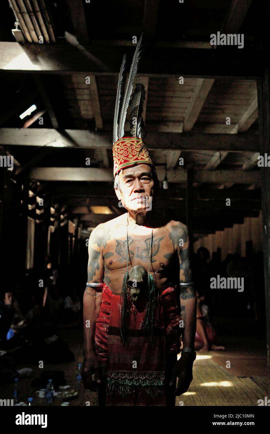 Portrait of Ramping, an elder, in traditional attire after the welcome ceremony of an ecotourism event at the longhouse of traditional Dayak Iban community in Sungai Utik, Batu Lintang, Embaloh Hulu, Kapuas Hulu, West Kalimantan, Indonesia. An elder with many traditional tattoos on his body, Mr. Ramping was one of the oldest persons in the community, holding an important role in rituals and traditions. Stock Photo