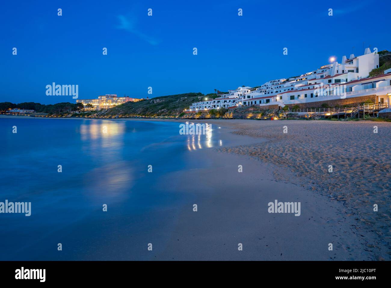 Hotels and whitewashed buildings overlooking beach at dusk in Arenal d'en Castell, Es Mercadal, Memorca, Balearic Islands, Spain, Europe Stock Photo