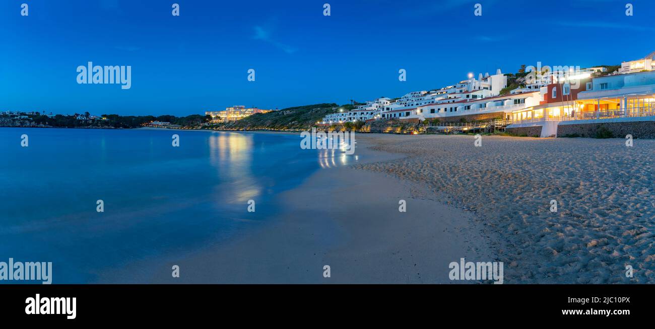 Hotels and whitewashed buildings overlooking beach at dusk in Arenal d'en Castell, Es Mercadal, Memorca, Balearic Islands, Spain, Europe Stock Photo