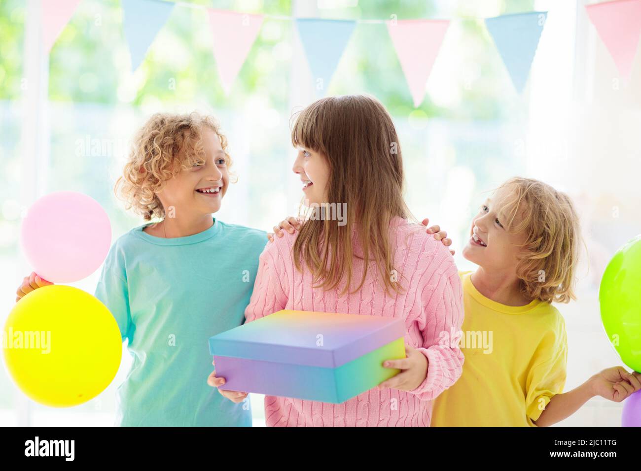 Kids birthday party. Child blowing out candles on colorful cake. Little