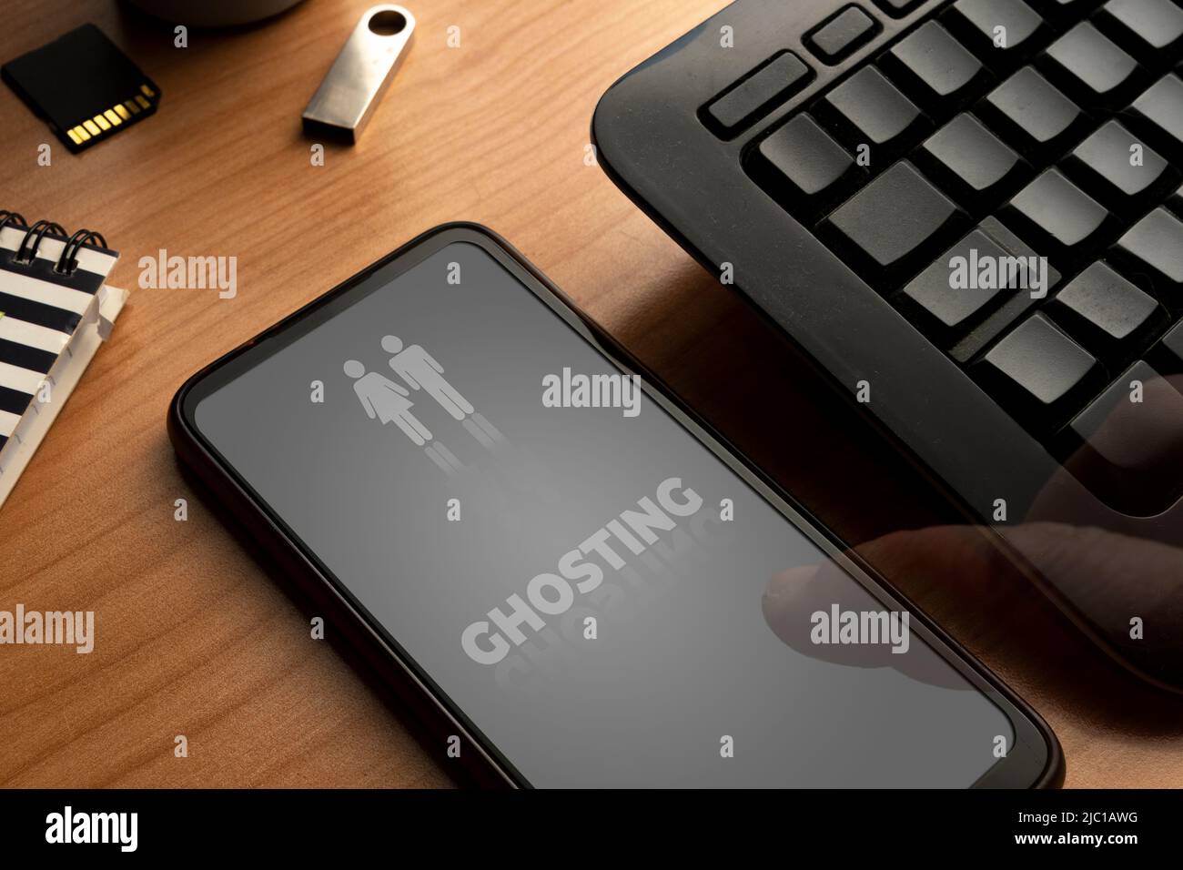 Ghosting concept: smartphone with the word ghosting on display and two disappearing people Stock Photo