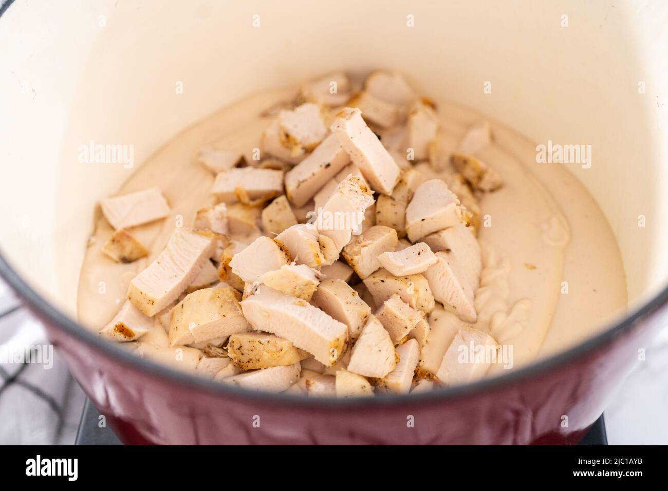 Mixing ingredients in an enameled dutch oven to prepare chicken alfredo