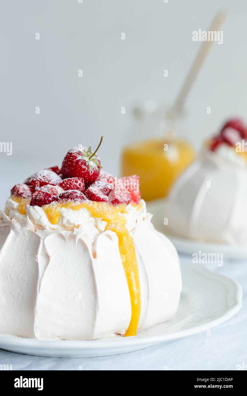 Classic Pavlova dessert with strawberry, whipped cream and lemon curd. Stock Photo