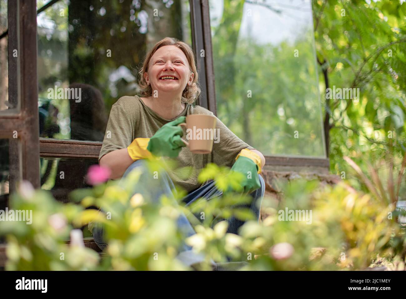 Low angle view of a mature woman drinking cup of tea while gardening Stock Photo