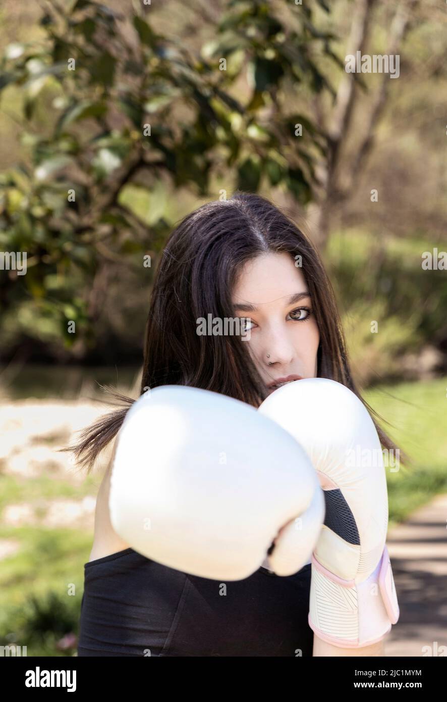 young female boxer with white gloves in a park Stock Photo