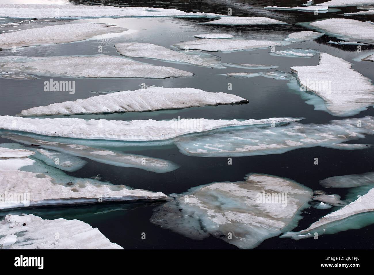 Ice floe melting on mountain lake. Cracked ice blocks covered with snow