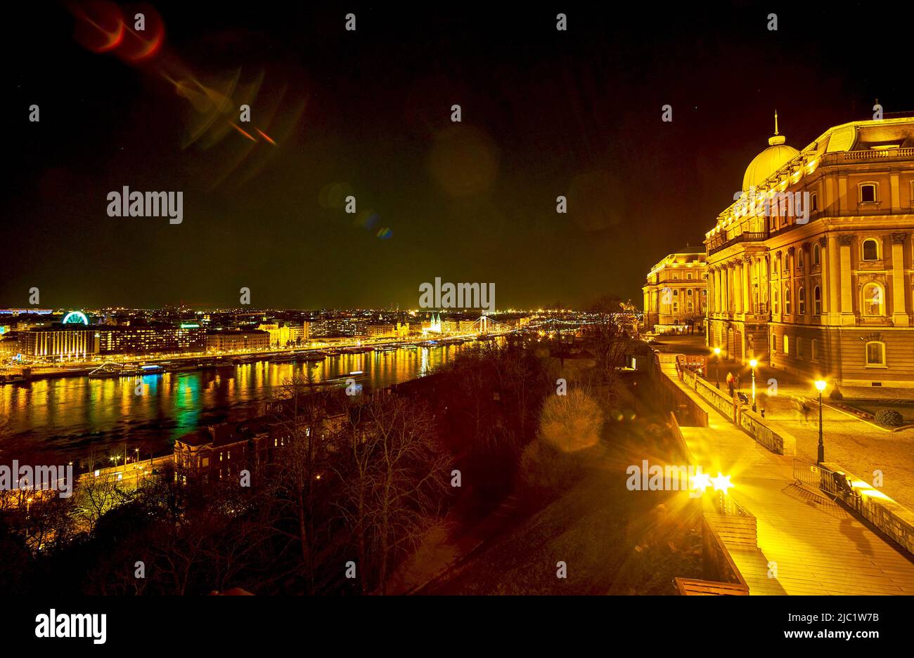 The bright night illumination of Buda Castle on Castle Hill and buildings on embankment of Danube river, Budapest, Hungary Stock Photo