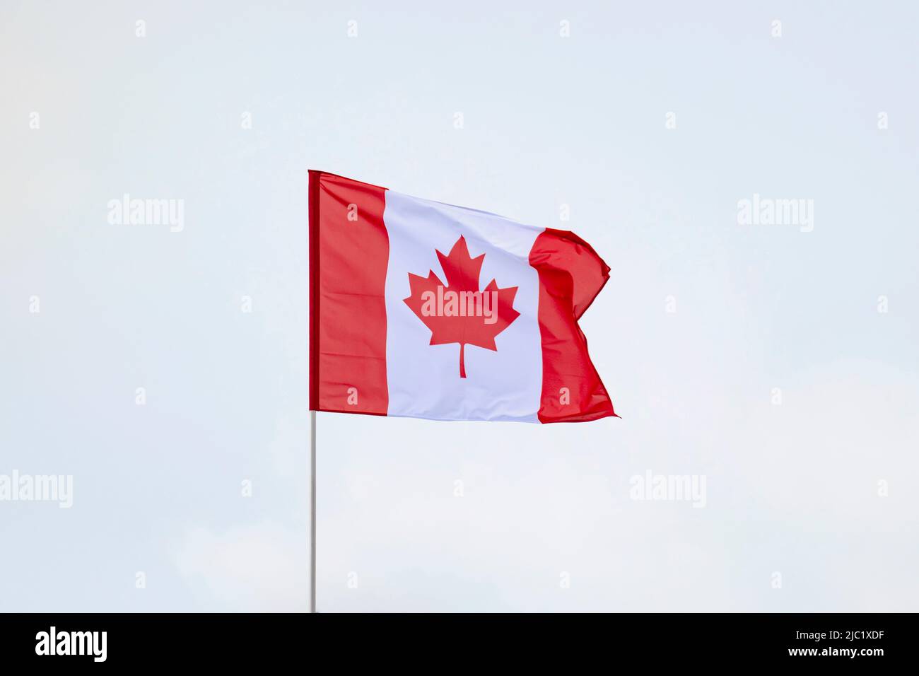 Flag of Canada developing against a clear blue sky Stock Photo