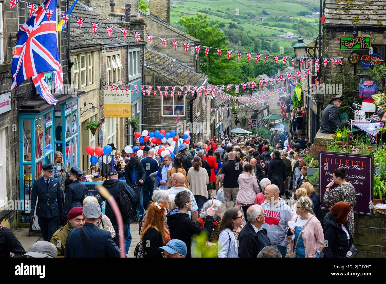 Haworth 1940's weekend (busy crowded scenic Main Street decorated in red white blue Union Jacks, popular family day-out) - West Yorkshire, England UK. Stock Photo