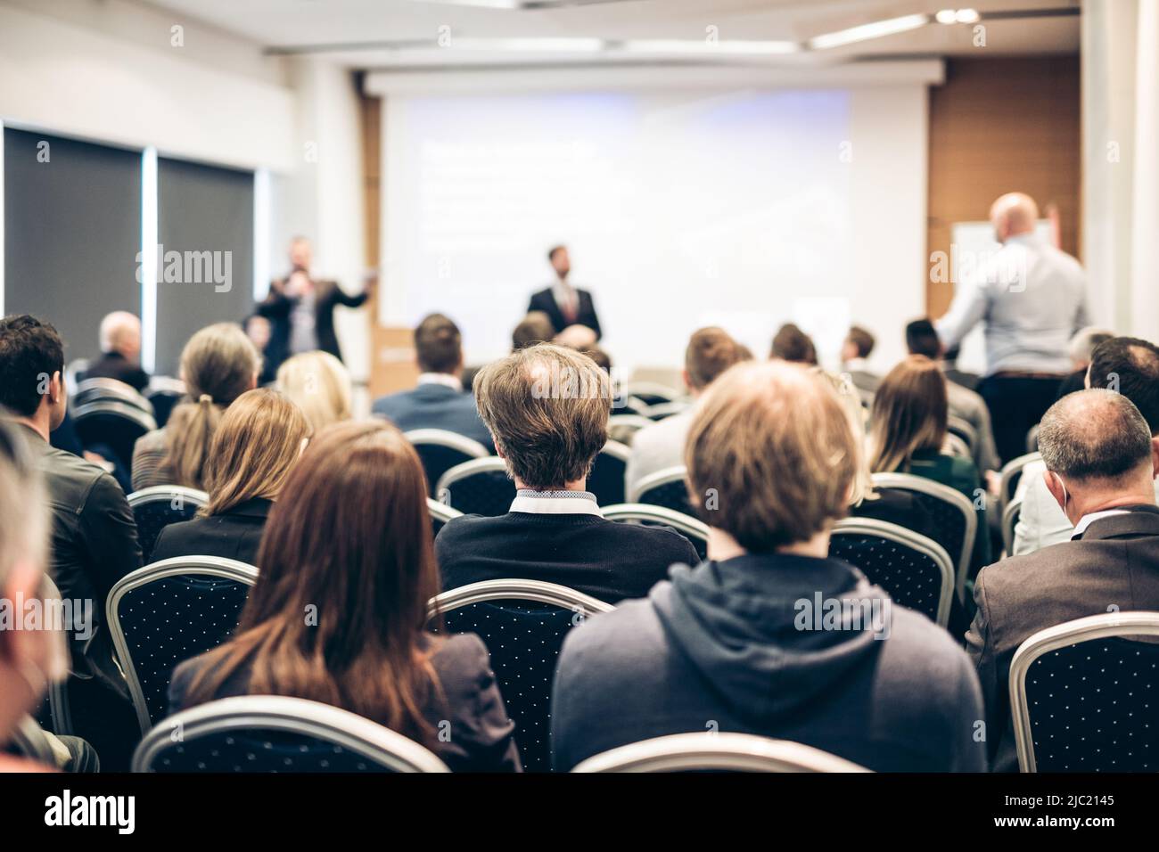 I have a question. Group of business people sitting in conference hall. Businessman raising his arm. Conference and Presentation. Business and Stock Photo