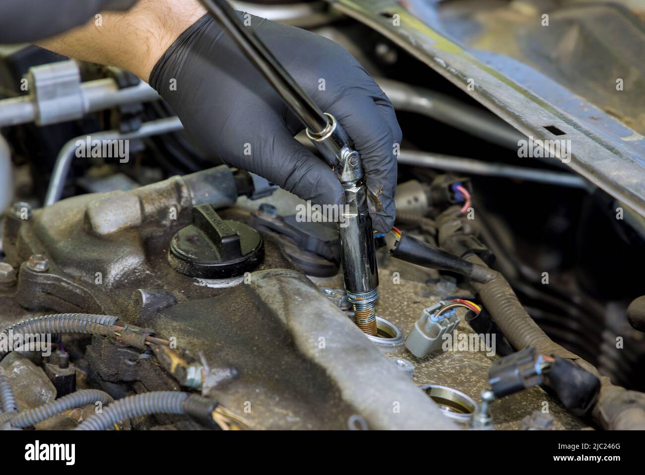 Auto mechanic using special tools with unscrews an old spark plug from