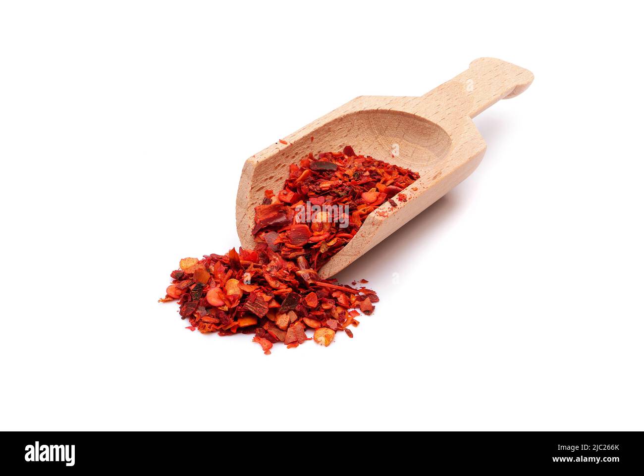 ground dried chili pepper flakes in wooden scoop isolated on white