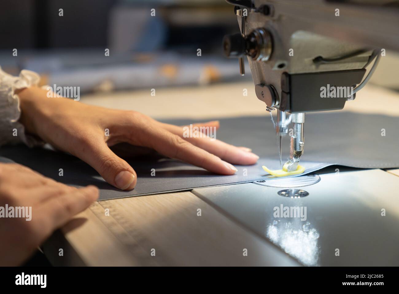 Closeup of female tailor work on sewing machine stitch fabric patterns for clothes. Garment